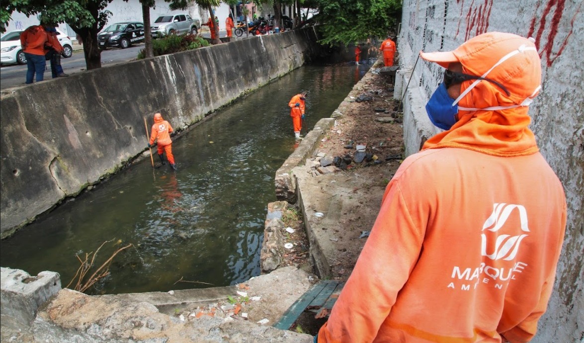 operários limpando um canal 